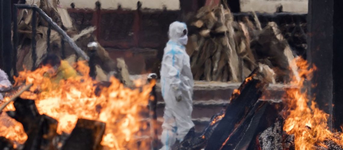 NEW DELHI, INDIA - APRIL 20: A man wearing PPE (Personal Protection Equipment) performs the last rites to his relative who died of the Covid-19 coronavirus disease at a crematorium on April 20, 2021 in New Delhi, India. Covid-19 cases are spiralling out of control in India, with daily infections approaching 300,000, according to health ministry data, bringing the nationwide tally of infections to almost 14 million. The latest wave has already overwhelmed hospitals and crematoriums. (Photo by Anindito Mukherjee/Getty Images)